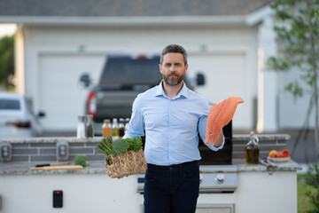 Chef barbecuing seafood. Backyard BBQ. Man cook fish. Man with barbeque roast fish outdoor. Grilling and barbecue. BBQ and grill. Hispanic man preparing herb crusted salmon fish in barbecue