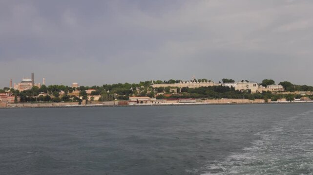 Panoramic view of Istanbul's historic peninsula across the Bosphorus Strait, featuring Hagia Sophia and Topkapi Palace under a cloudy sky.