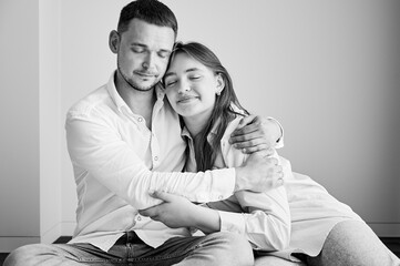 Portrait of father and teenage daughter hugging each other at home. Cute moment of dad and child in glasses showing their love to each other. Lovely spending time with family. Black and white image.