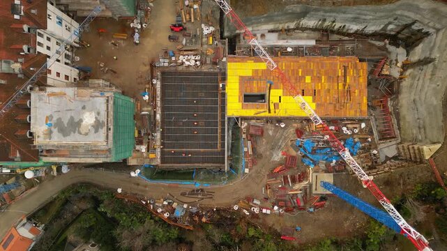 Aerial drone view of large construction site in Thailand with tower crane, high rise building and industrial facilities. Urban development, modern infrastructure heavy construction activity in Asia