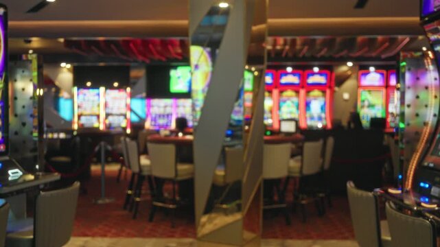 Casino gaming floor with slot machines and mirrored pillars, blurred bokeh foreground and defocused lights, neon color wash background interior; background backplate copyspace template.