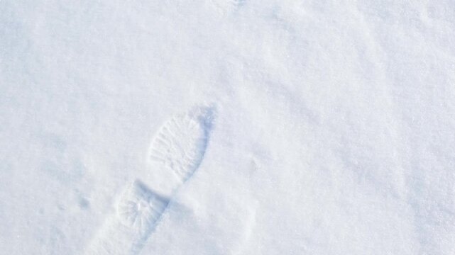 A solitary human footprint pressed deep into soft fresh white snow on a cold winter morning
