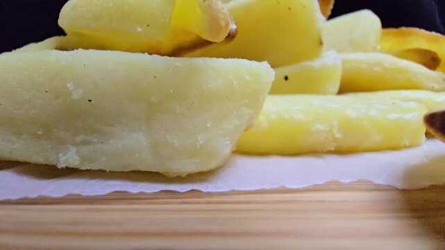 High-quality macro shot of crispy, golden air-fryer French fries, oil-free and healthy, on a natural wooden board with a dark minimalist background&mdash;ideal for clean eating and modern food branding.