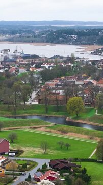 looks across green ramparts moats along glomma river red roofed buildings paths layered hills shape fredrikstad norway drone view historic fortifications defensive aerial 
