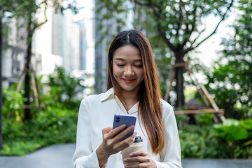 Fototapeta premium Asian young businesswoman chatting on smartphone while walk in the city. 
