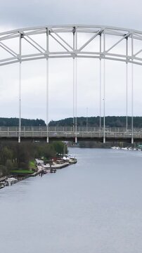 mid centers white steel arch bridge glomma river red vehicle green banks neighborhoods appear fredrikstad norway range drone view aerial urban infrastructure roadway 