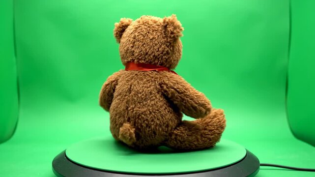 Isolated brown plush teddy bear sitting completely still and rotating slowly on a flat green screen surface for easy alpha channel keying and compositing into any scene transparent, plush, brown