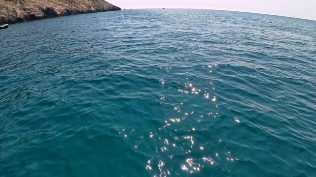 POV shot of a yellow pedal boat on blue sea water with a red buoy Feet are visible suggesting.