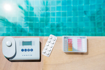 Digital water tester and pool tester on swimming pool edge with space on blue water background, summer outdoor day light, water quality testing technology