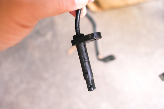 Car Wheel Speed Sensor, A close-up of a black ABS wheel speed sensor being held, a critical component for anti-lock braking and traction control systems.