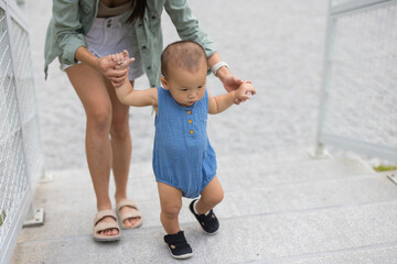 Mum guiding baby walking up stairs at park