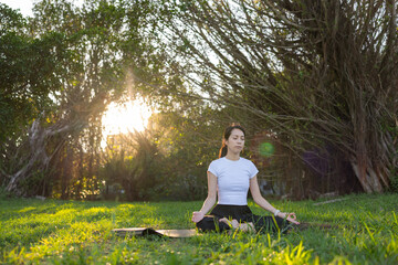 Woman sitting on grass practicing calm meditation outdoors