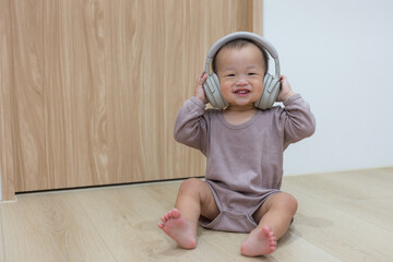 Happy baby wearing headphones and dancing at home