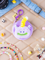 A close-up of a soft  purple plush wallet featuring a fun and adorable monster design