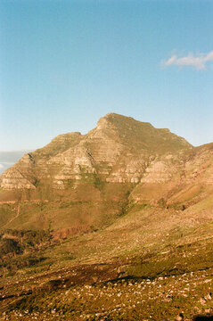 Majestic mountain stands tall against clear sky with rocky terrain