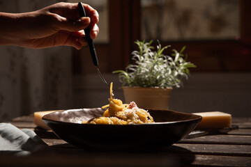 A table by the window with a plate of spaghetti carbonara.