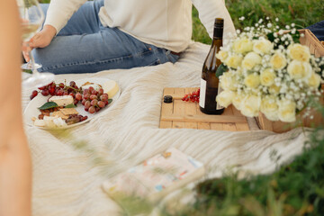 Picnic wine, cheese, and flowers on blanket