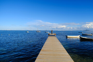Fototapeta premium Woman walks along a wooden boardwalk in the sea