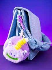 A close-up of a soft  purple plush wallet featuring a fun and adorable monster design on blue bag