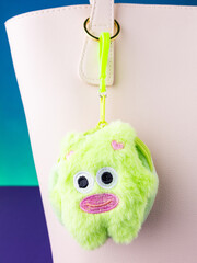 A close-up of a soft, green plush wallet featuring a cute and funny green monster design on white bag