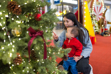 Mother taking baby to see Christmas tree