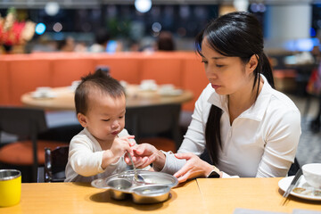 Mother feeding baby meal at restaurant indoors