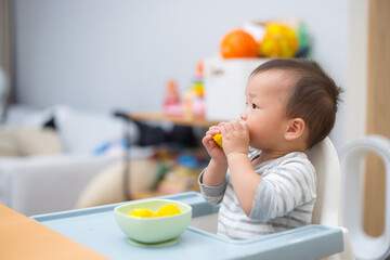 Baby eating corn on high chair at home