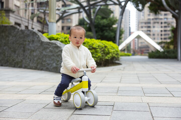 Toddler learning bicycle ride outside with parent