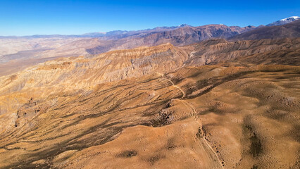 Fototapeta premium Panoramic view of orange eroded hills and white Himalayan peaks