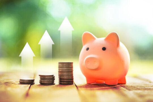A pink piggy bank with coins and money placed on a table representing savings and finance
