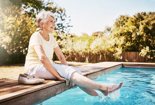 Smile, sunny and elderly woman at pool with break, positive attitude or weekend enjoyment in retirement. Happy, bokeh or senior person in backyard with good mood, calm or Sunday rest with fresh air.