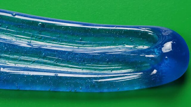 Isolated macro shot of a thick swatch of cosmetic blue gel sliding and smearing across a seamless, pure green screen background for easy keying clean, close up, easy keying