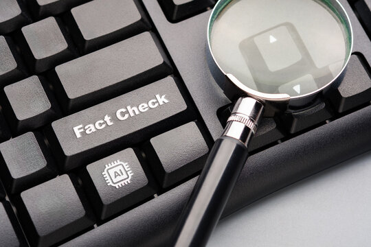 Magnifying glass over a keyboard highlighting fact check and AI symbol, representing verification of digital information, data accuracy, critical thinking and responsible use of technology
