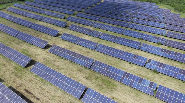 Aerial drone footage of solar panels at a renewable energy plant in a natural landscape.