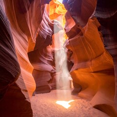 A canyon with a beam of light illuminating the wavy orange and white rock walls