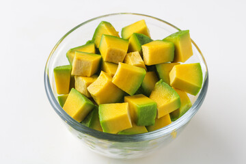 Bowl of diced avocado pieces displayed in a clear glass bowl on a white background.
