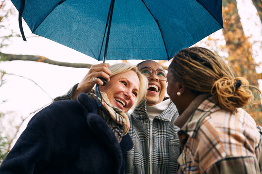 Low angle view of carefree childhood friends enjoying under umbrella in back yard