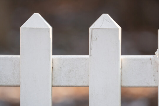white Pickett fence section made from a composite venial material designed for outdoor use and easily power washed is developing a moldy algae on its surface