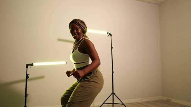 Charismatic african woman with long braids performing a dynamic afrodance routine. Graceful dancer moving rhythmically with passion in a studio