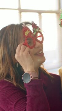 Vertical video: Hugging woman in maroon top with red tree specs adjusting them reaching man at home