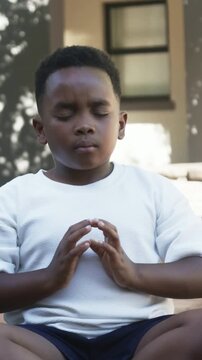 Vertical video: Starting breath, child in white tee, dark shorts lowering arms on steps, meditating