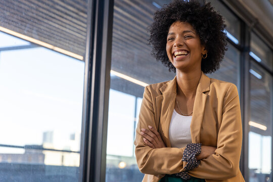 African american woman smiling by windows in office wearing blazer, copy space