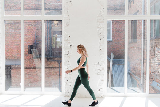 Girl in sportwear walking at room with panoramic window