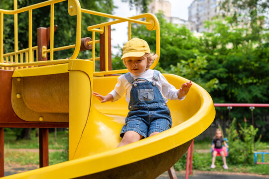 A little boy riding on a yellow slide at a playground
