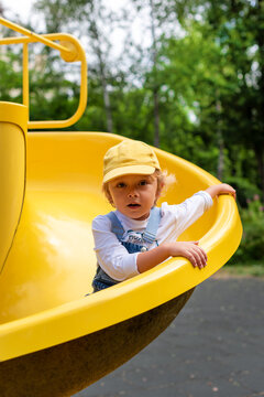 A little boy riding on a yellow slide at a playground