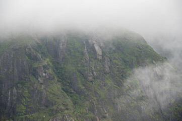 Close-up view of a mountain at Chathurangapara, Idukki, Kerala, highlighting rocky textures, lush greenery, native trees, and drifting monsoon clouds across the Western Ghats.