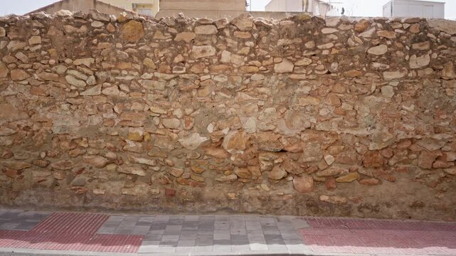 Stone wall texture on urban street with rough mortar and exposed stones; background backplate copyspace.