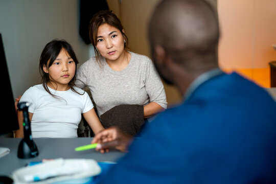 Mother sitting with daughter while listening carefully to doctor's advice during hospital visit