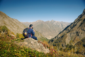 Fototapeta premium Male Hiker with Backpack Sitting on Rock Overlooking a remote Valley in the kashmir mountains