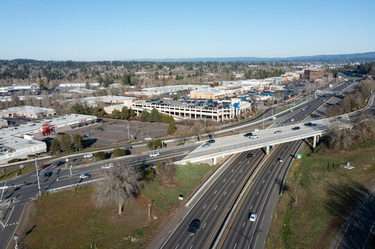 Tigard, Oregon, USA - Jan 24, 2026- Aerial drone picture of OR 217 highway morning traffic, showing vehicles driving north and south with CarMax dealership and Nordstrom shopping area buildings behind